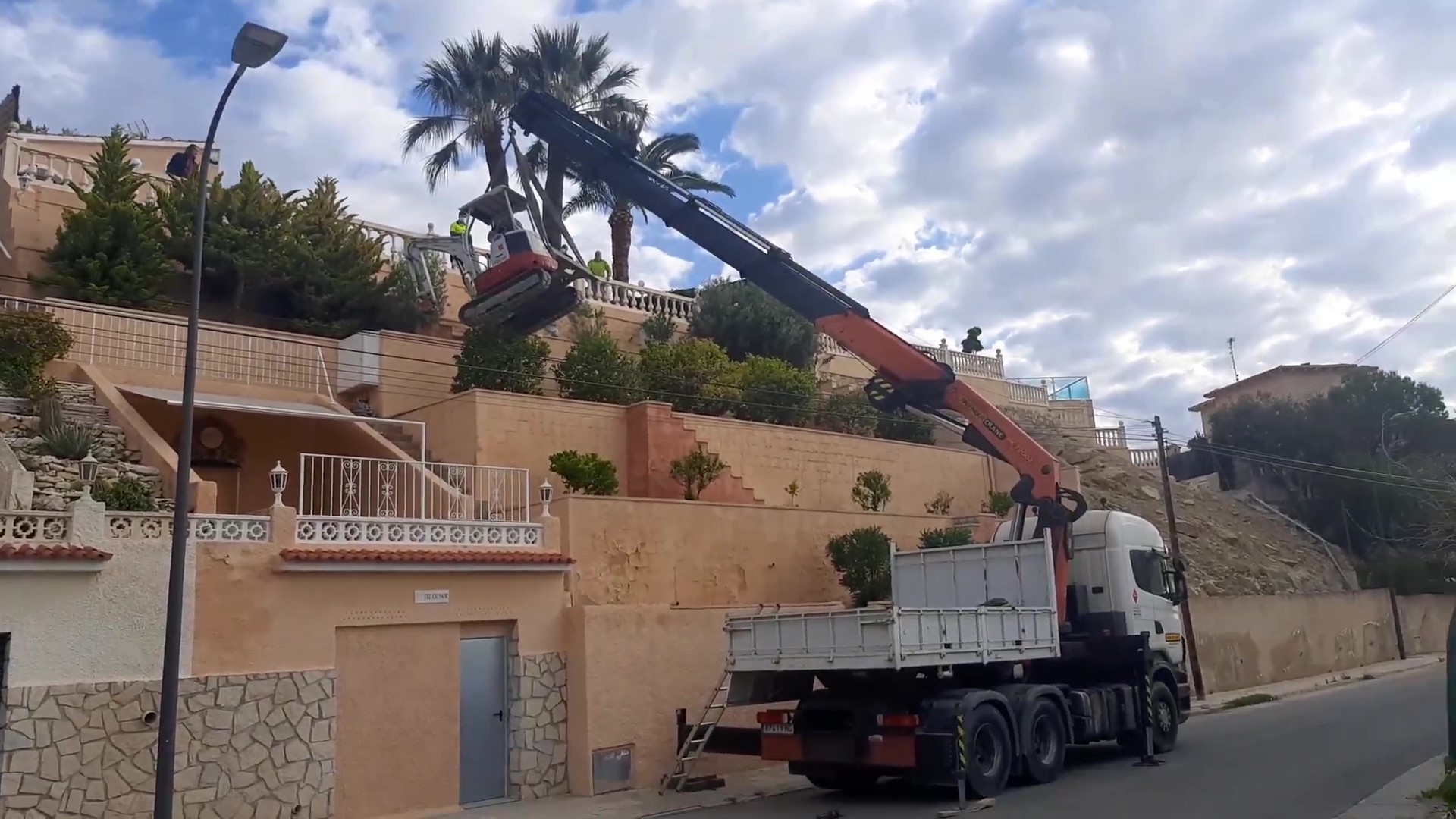 Miniexcavadora propia izada con camión grúa para excavación de piscina en parcela sin acceso en Alicante